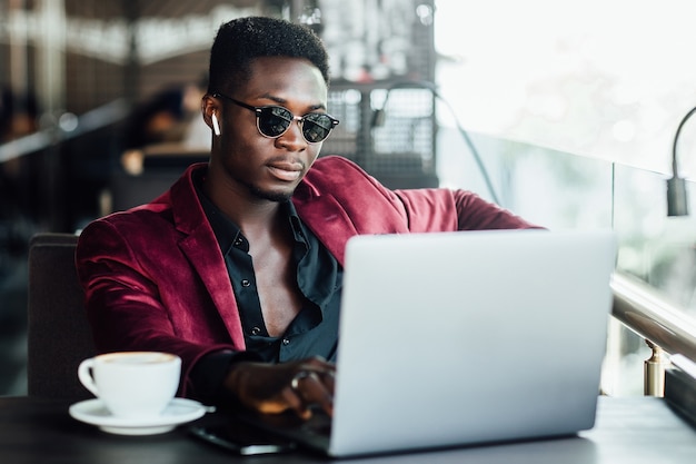 Young businessman sitting next to laptop and watching something.