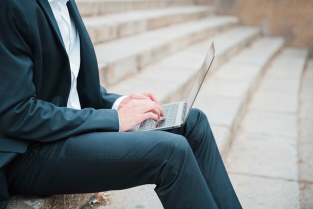 Young businessman sitting on staircase using laptop