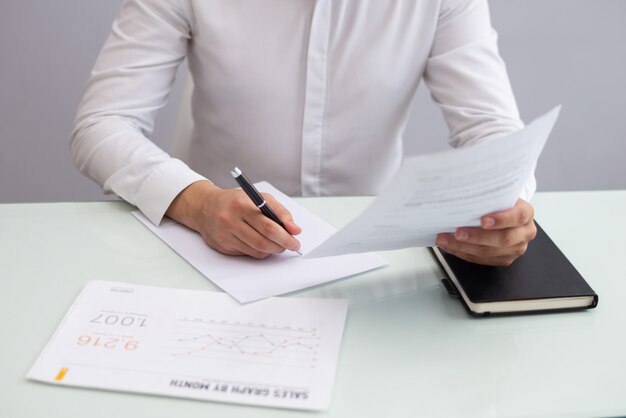 Young businessman sitting at table and working with papers