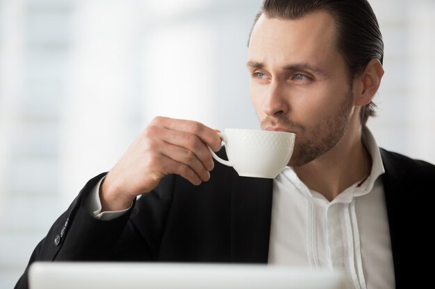 Young businessman takes coffee-break at workplace