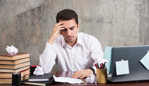 Free photo young businessman thinking hard at the office desk.