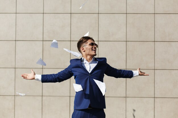 Young businessman throughs away papers standing on the street