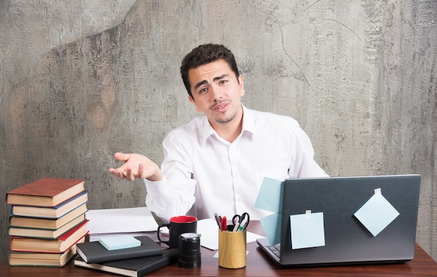 Free photo young businessman tiredly looking at camera at the office desk.