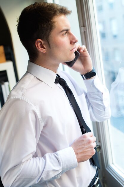 Young businessman using his mobile phone in office.