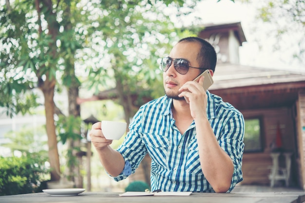 Young businessman using smartphone while working in the home garden.