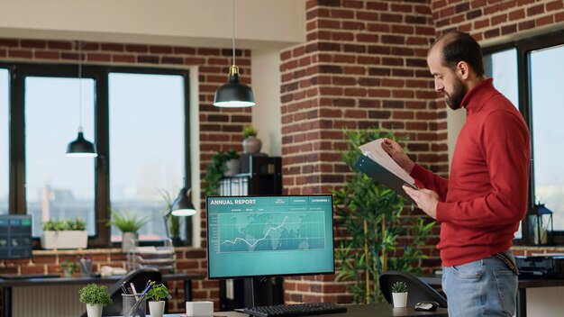 Young businessman using trade market profit data on screen to create financial investment, looking at stock charts statistics. Male broker analyzing hedge hund trend and forex exchange.