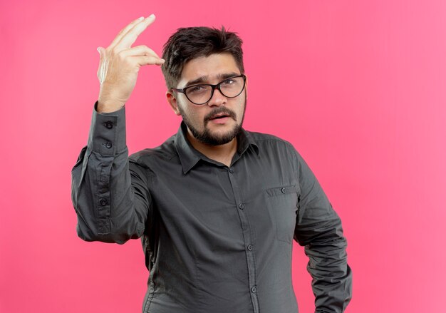 young businessman wearing glasses raising hand isolated on pink wall