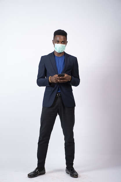 Young businessman wearing a suit and face mask using his phone