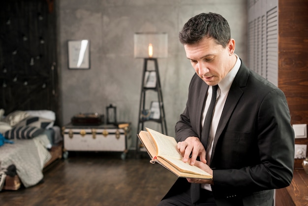 Young businessman with book relaxing at home