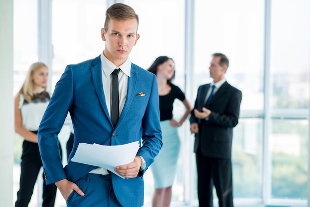 Young businessman with documents standing in office