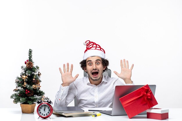 Young businessman with funny santa claus hat feeling shocked about the news he hears in the office