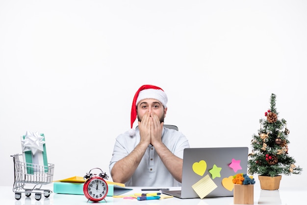 クリスマスを祝い、彼の口を覆っているオフィスで驚いた表情を持つ青年実業家 無料写真
