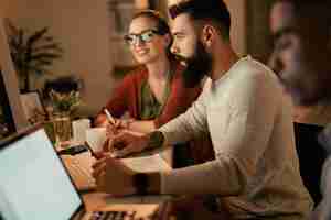 Free photo young businessman working on desktop pc while being with his coworkers in the office