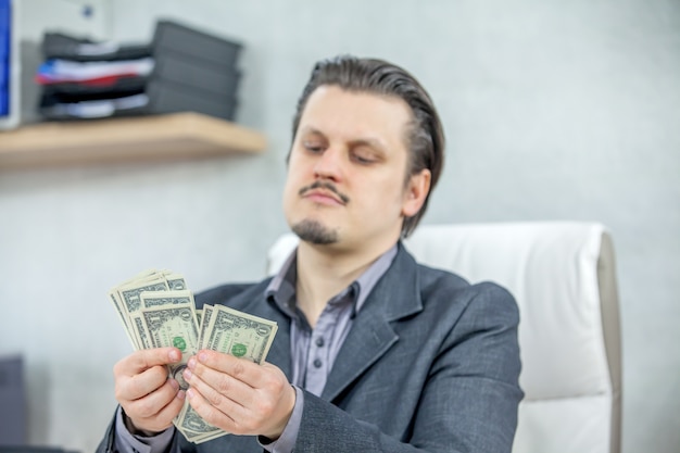 Young businessman working from his office and counting cash money