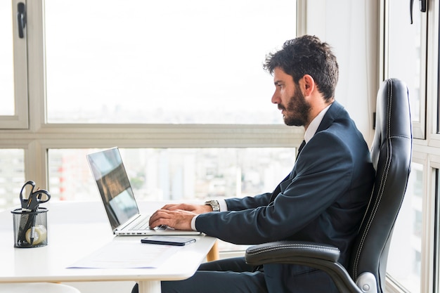 Young businessman working on laptop at workplace