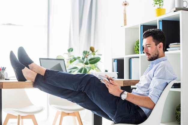 Young businessman writing on notepad while sitting in office