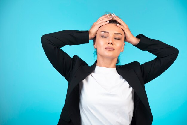 Young businesswoman in black blazer having a headache.