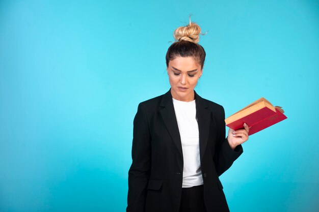 Young businesswoman in black blazer holding a taskbook and checking the meetings.