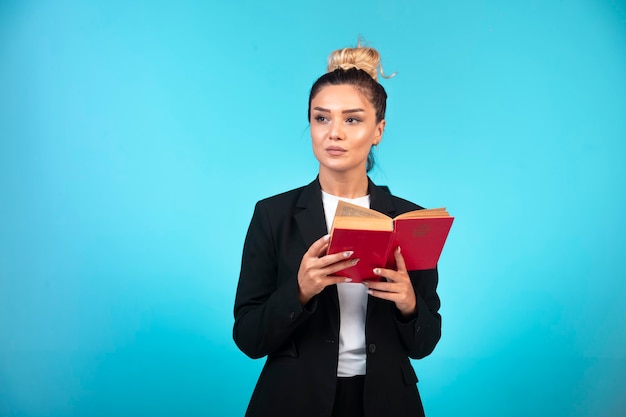 Young businesswoman in black blazer holding a taskbook and thinking. 