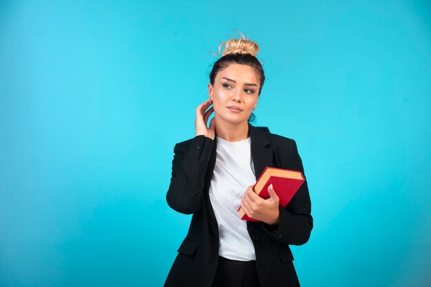 Young businesswoman in black blazer holding a taskbook .