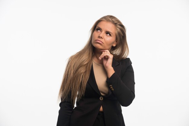 Young businesswoman in black suit looks doubtful .