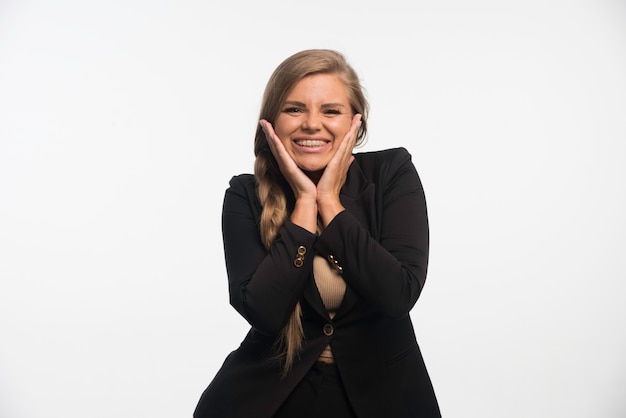 Free photo young businesswoman in black suit looks happy and cheerful.