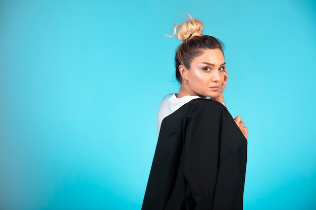 Young businesswoman in bun holding a black blazer and looks confident.