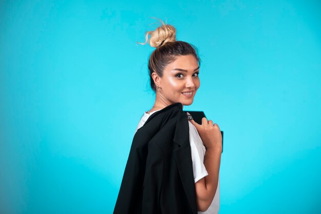 Young businesswoman in bun holding a black blazer and smiling. 