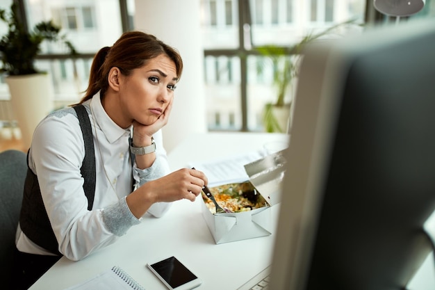 Young businesswoman eating and thinking of something in the office