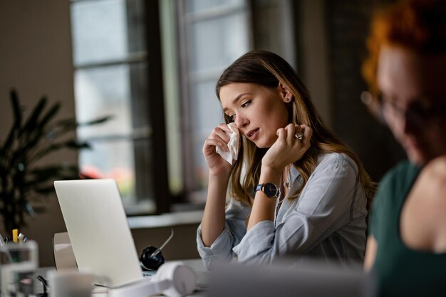Молодая деловая женщина чувствует себя плохо во время работы за компьютером в офисе