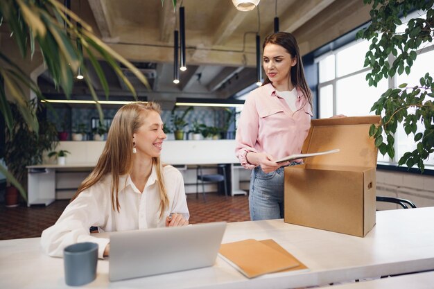 Young businesswoman holding box of personal belongings about to leave office after quitting job