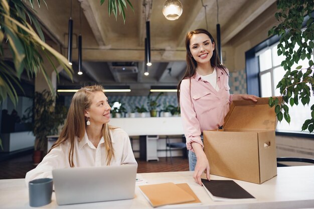 Young businesswoman holding box of personal belongings about to leave office after quitting job