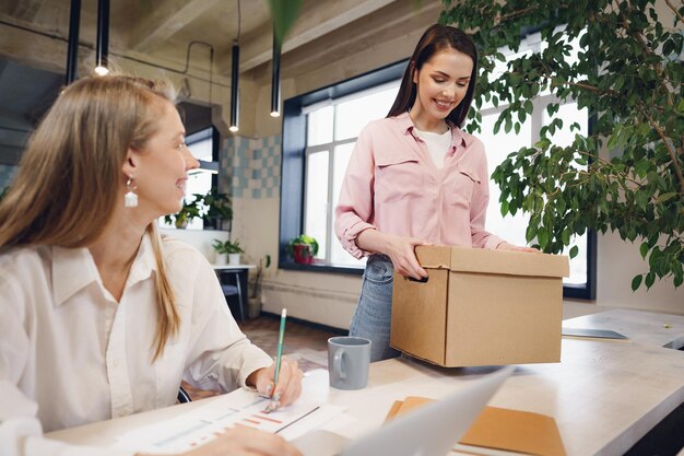 Young businesswoman holding box of personal belongings about to leave office after quitting job