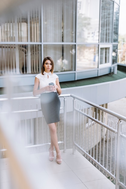 Young businesswoman holding coffee cup standing in the balcony