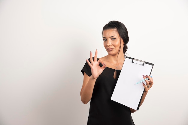 Young businesswoman holding documents and making ok sign.
