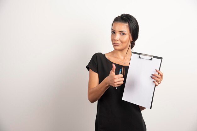 Young businesswoman holding documents and showing thumb up.