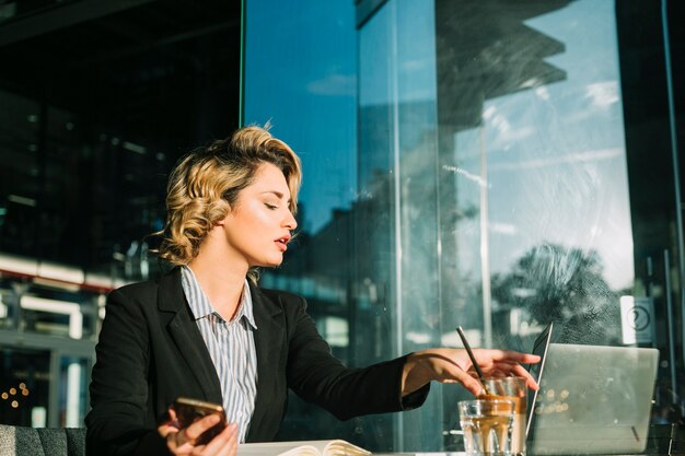 Young businesswoman holding glass of chocolate milkshake in restaurant