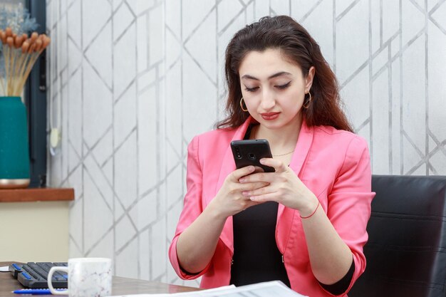 Young businesswoman holding her phone and writing message High quality photo