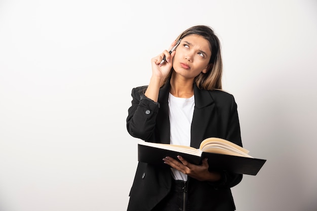 Young businesswoman holding an opened clipboard with pencil .