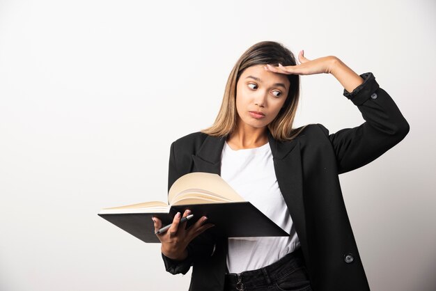 Young businesswoman holding an opened clipboard with pencil . 