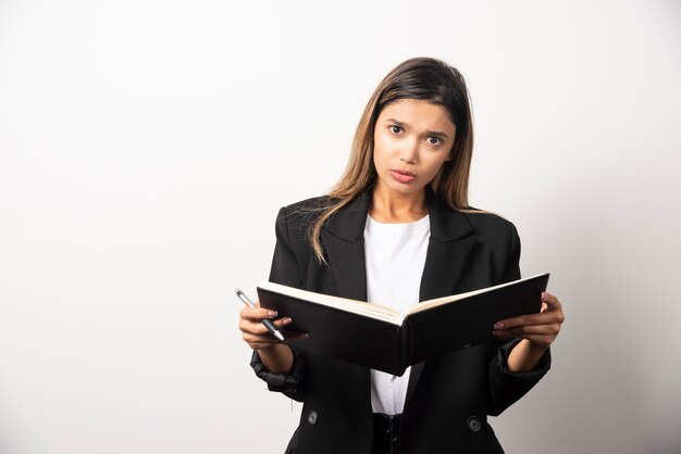 Young businesswoman holding an opened clipboard with pencil . 