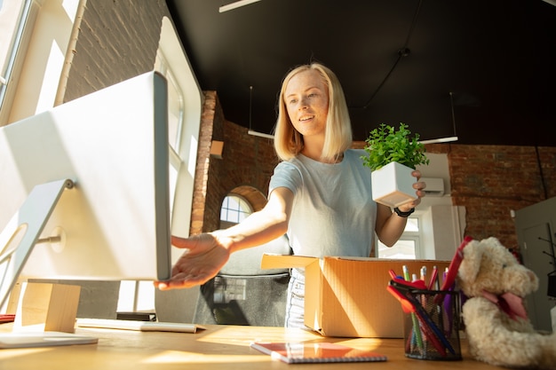 A young businesswoman moving in the office, getting new work place. Young caucasian female office worker equips new cabinet after promotion