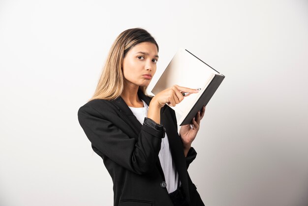 Young businesswoman pointing at clipboard . 