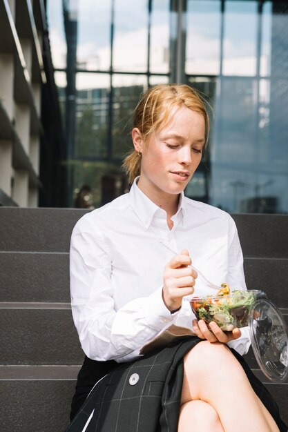 昼食をとって階段の上に座っている若い実業家