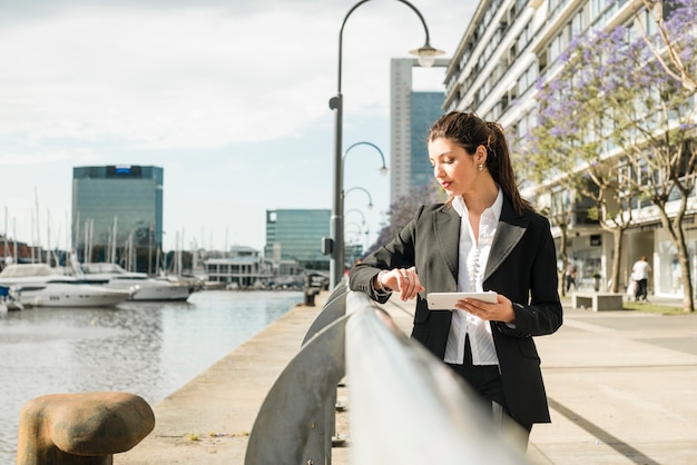 Free photo young businesswoman standing near the harbor checking the time