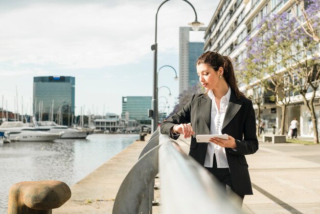 Young businesswoman standing near the harbor checking the time