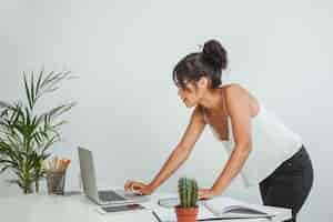 Free photo young businesswoman standing up and working with laptop