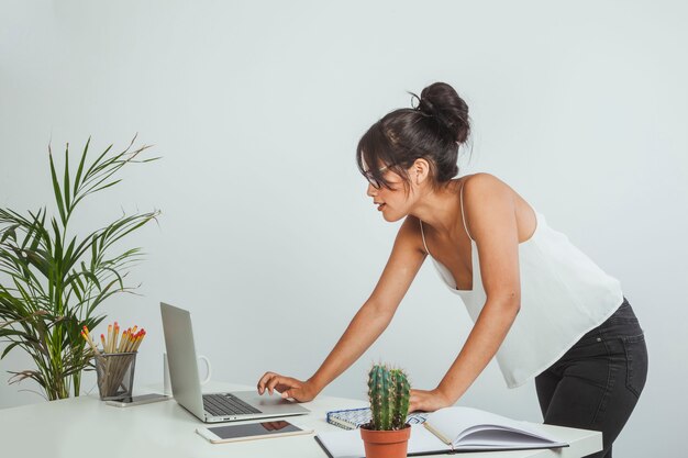 Young businesswoman standing up and working with laptop