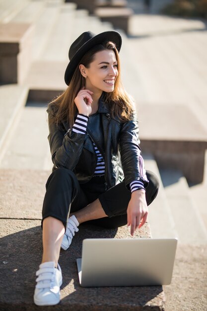 Young businesswoman student girl works with her brand laptop computer in the city centre