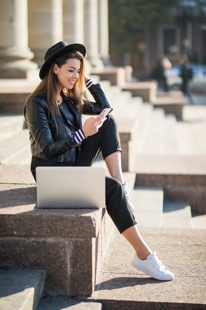 Young businesswoman student girl works with her brand laptop computer in the city centre